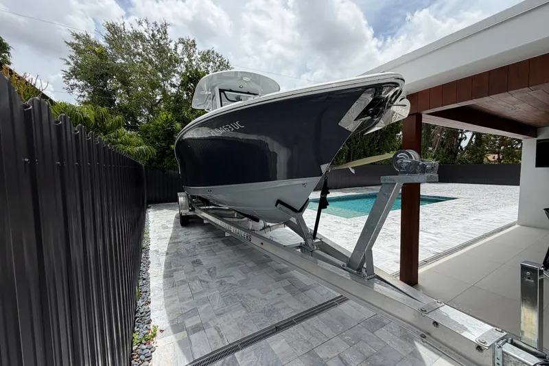 Slide: The Image of 2026 Sea Hunt Ultra 265SE boat on trailer beside pool and modern house. - 1