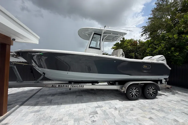 Slide: The Image of 2026 Sea Hunt Ultra 265SE boat on trailer, parked outdoors under cloudy sky. - 2