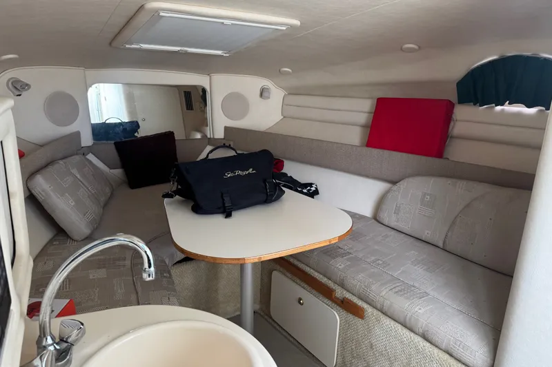 Slide: The Image of Interior of 2002 Sea Ray Sundancer 260, featuring cozy seating and compact table setup. - 19