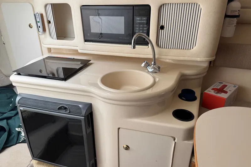 Slide: The Image of Compact kitchen area in a 2002 Sea Ray Sundancer 260 boat, featuring a sink, microwave, and stove. - 20