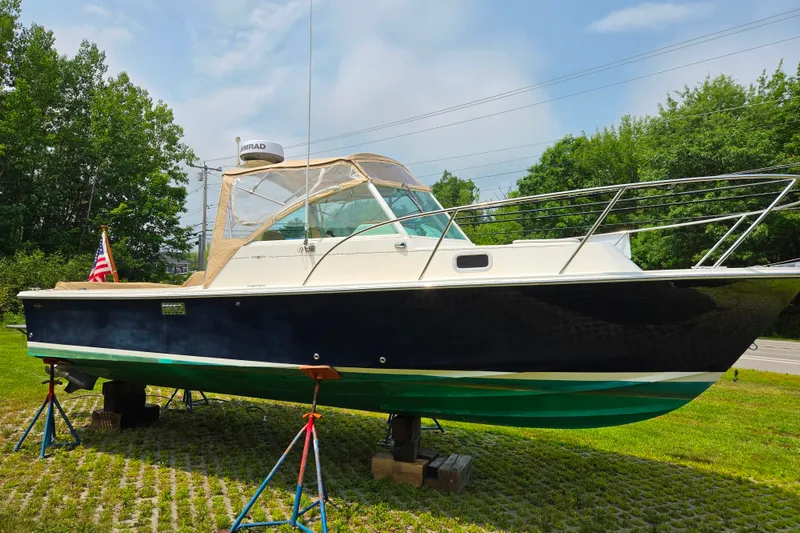 The Image of 2004 Hunt Yachts Surfhunter 25 on stands, displayed outdoors with lush greenery. - 0