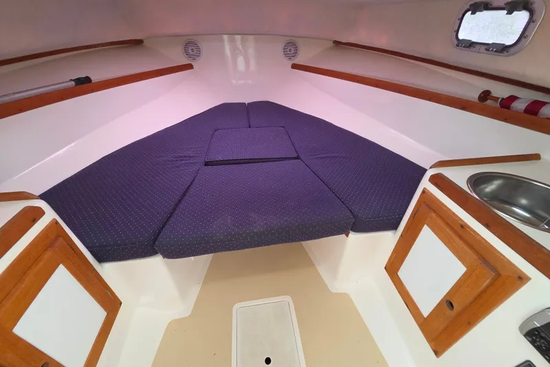 Slide: The Image of 2004 Hunt Yachts Surfhunter 25 cabin interior with blue cushions and wooden accents. - 28