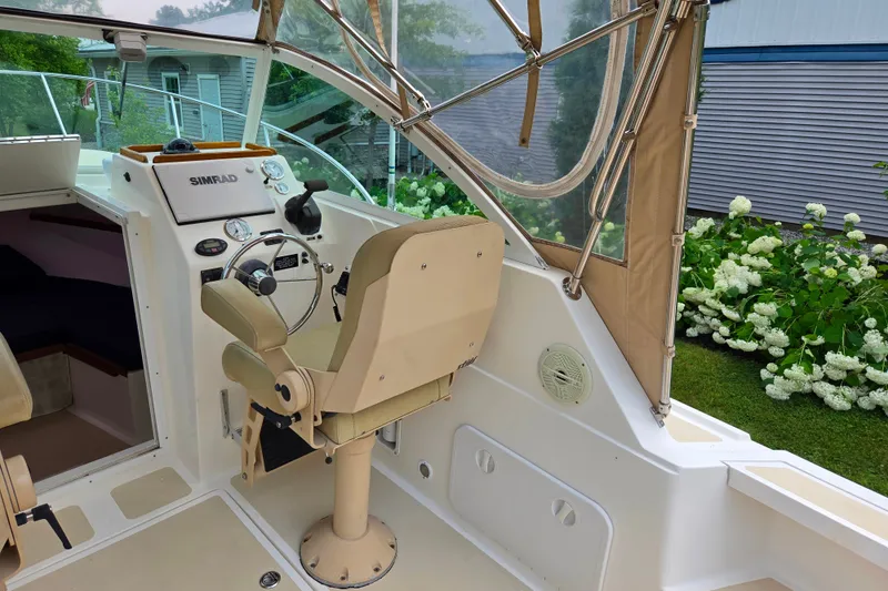 Slide: The Image of 2004 Hunt Yachts Surfhunter 25 cockpit with helm, beige seating, and Simrad navigation system. - 15