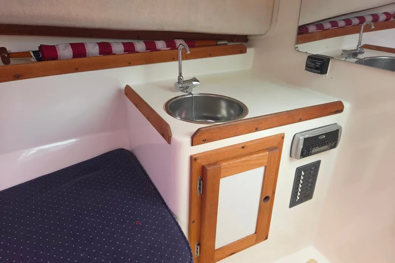Slide: The Image of 2004 Hunt Yachts Surfhunter 25 cabin interior with sink, wooden cabinetry, and control panel. - 35