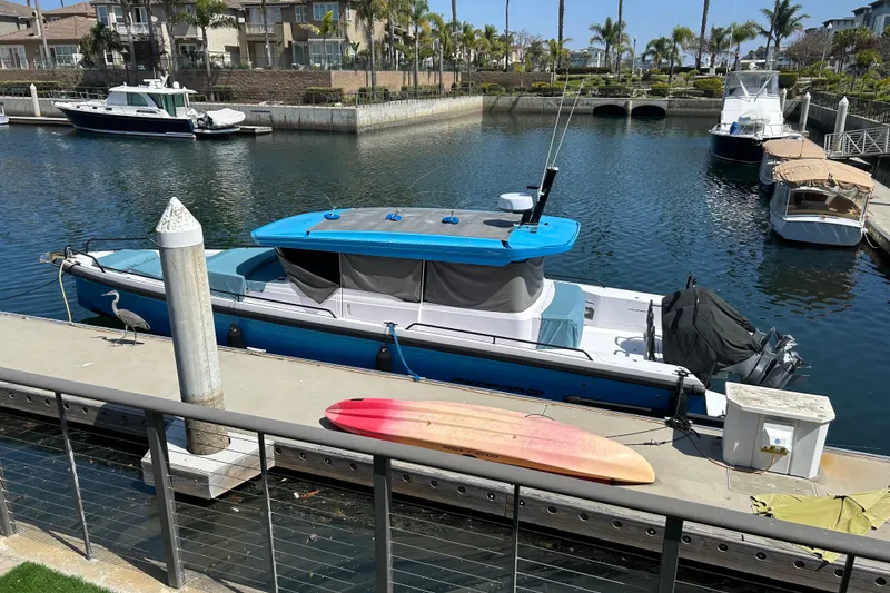 Slide: The Image of 2024 Axopar 37 XC Cross Cabin docked in a marina with a kayak nearby. - 2