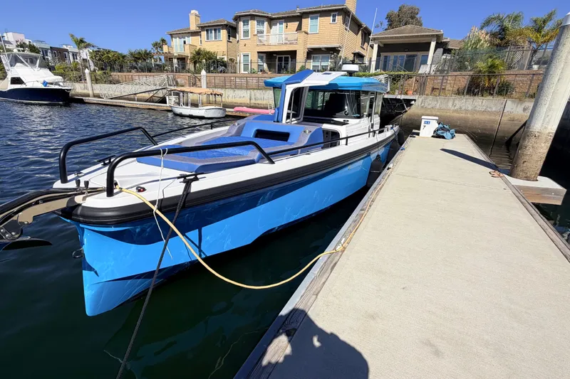 Slide: The Image of 2024 Axopar 37 XC Cross Cabin docked in a marina, showcasing sleek design and vibrant blue color. - 14