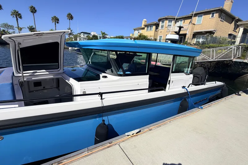 Slide: The Image of 2024 Axopar 37 XC Cross Cabin boat docked, featuring sleek blue and white design. - 15