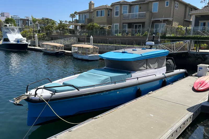 The Image of 2024 Axopar 37 XC Cross Cabin boat docked in a marina, with waterfront homes in the background. - 1