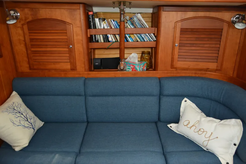 Slide: The Image of Cozy Sabre 402 yacht interior with blue sofa, nautical pillows, and wooden cabinets, 2002 model. - 106