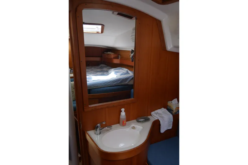 Slide: The Image of 2002 Sabre 402 yacht interior with wooden cabinetry, mirror, and compact sink area. - 93