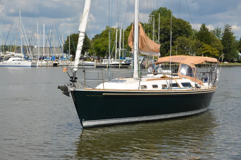 Slide: The Image of 2002 Sabre 402 sailboat docked in a marina, surrounded by other boats and lush greenery. - 13