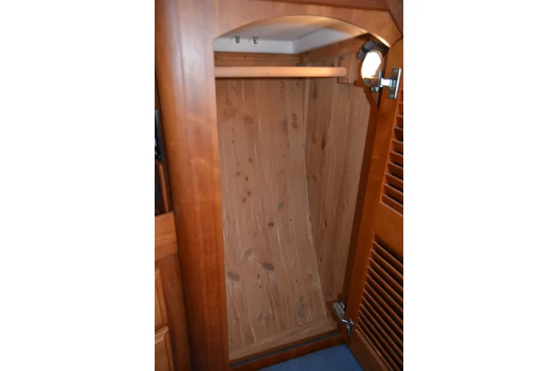 Slide: The Image of Wooden closet interior on a 2002 Sabre 402 yacht, featuring a hanging rod and light. - 135