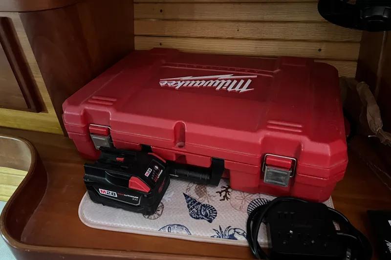 Slide: The Image of Red Milwaukee tool case and M28 battery on a wooden shelf in a Sabre 402 yacht. - 142