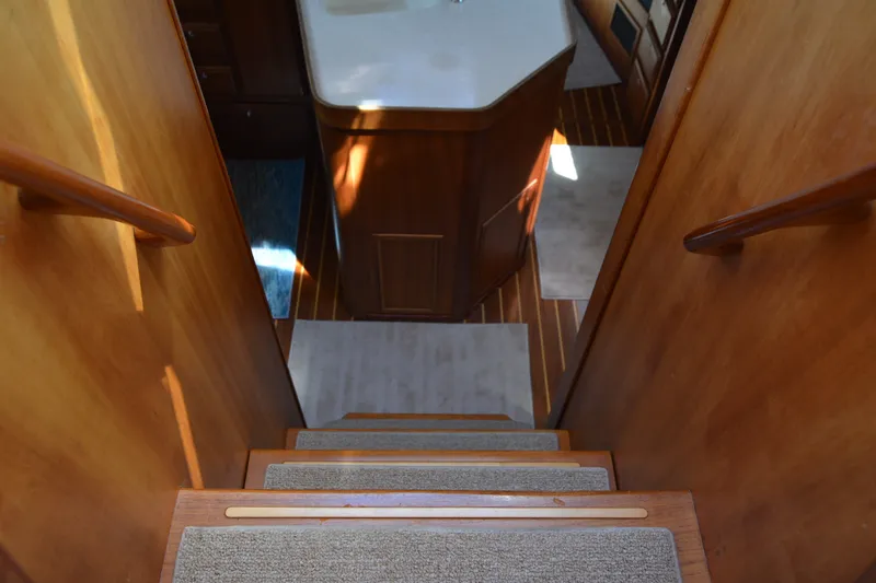 Slide: The Image of Interior stairs of a 2002 Sabre 402 yacht, featuring wooden handrails and carpeted steps. - 70