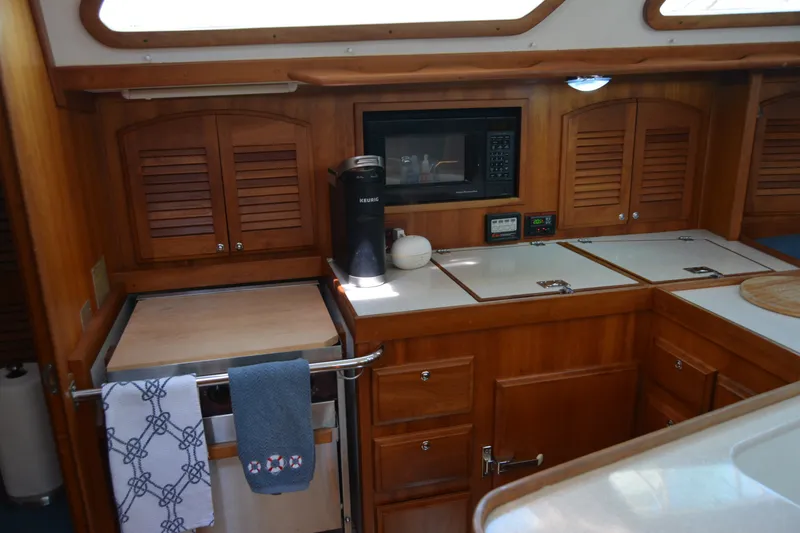 Slide: The Image of 2002 Sabre 402 yacht kitchen with wooden cabinets, microwave, and Keurig coffee maker. - 79