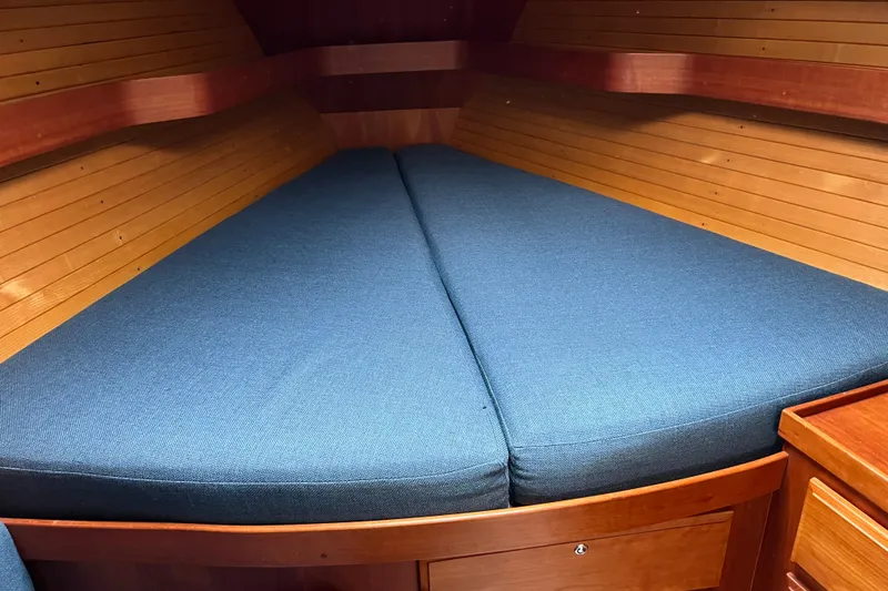 Slide: The Image of Interior of 2002 Sabre 402 sailboat with blue cushioned V-berth and wooden paneling. - 87