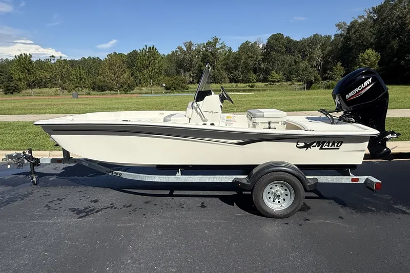 The Image of 2026 Mako Pro Skiff 15 CC boat on trailer, parked outdoors with Mercury engine. - 0