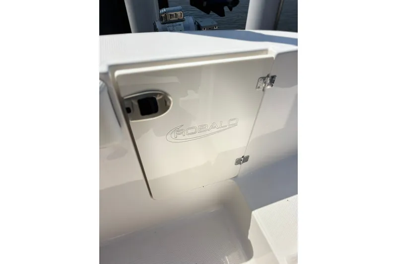 Slide: The Image of 2023 Robalo R272 Center Console storage compartment with logo and latch detail. - 40