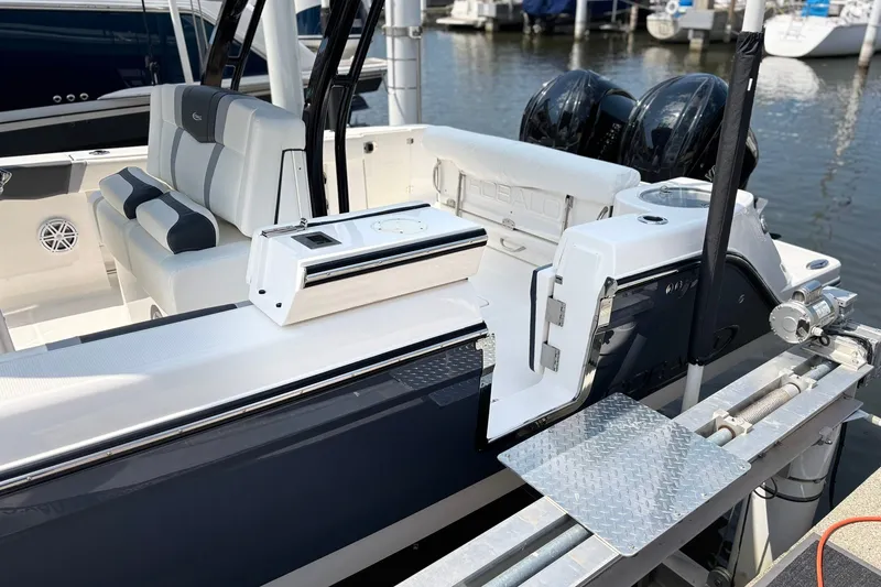 Slide: The Image of 2023 Robalo R272 Center Console boat interior with seating and dual engines at a marina. - 13