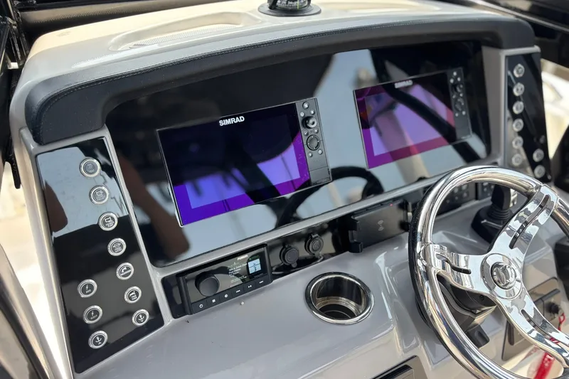 Slide: The Image of 2023 Robalo R272 Center Console dashboard with dual Simrad displays and chrome steering wheel. - 27
