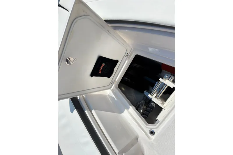 Slide: The Image of 2023 Robalo R272 Center Console storage compartment with open hatch and visible equipment. - 45