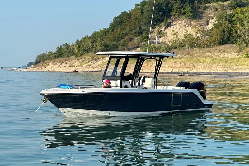 The Image of 2023 Robalo R272 Center Console boat anchored near a scenic shoreline. - 0
