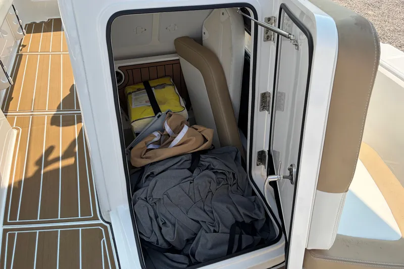 Slide: The Image of Storage compartment on 2022 Edgewater 230CC boat with life jacket and gear inside. - 14