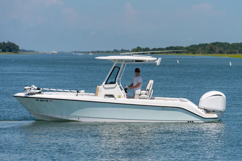 The Image of 2022 Edgewater 230CC boat cruising on a calm blue lake. - 0