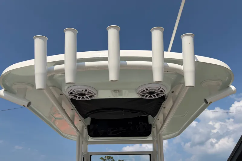 Slide: The Image of 2022 Edgewater 230CC boat top with rod holders and speakers against blue sky. - 22
