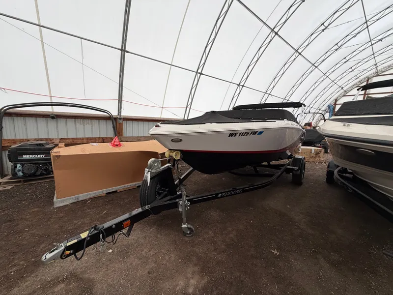 Slide: The Image of A 2017 Four Winns H180 SS boat on a trailer in a covered area. - 2