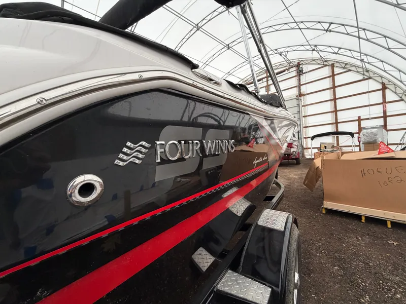 Slide: The Image of A 2017 Four Winns H180 SS boat in a storage facility, featuring a black hull with red accents. - 7