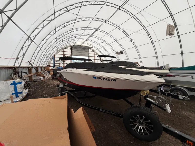 Slide: The Image of A 2017 Four Winns H180 SS boat is in a covered storage area on a trailer. - 1