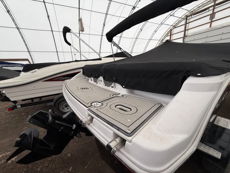 Slide: The Image of A 2017 Four Winns H180 SS with a black cover, parked in a covered area. - 8