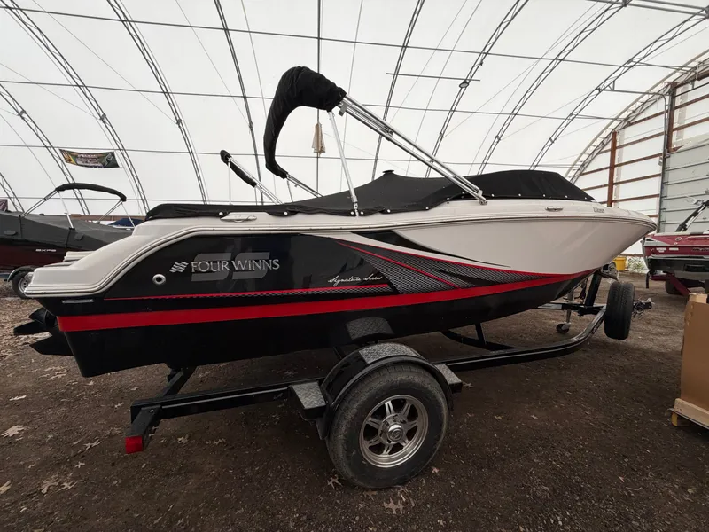 The Image of A 2017 Four Winns H180 SS boat on a trailer in a covered area. - 0
