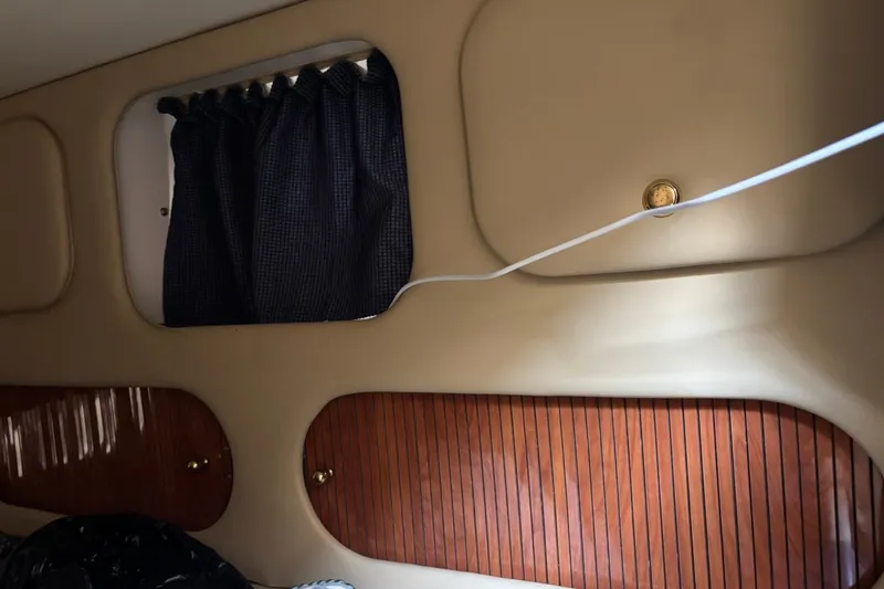 Slide: The Image of Interior of 2003 Rinker Fiesta Vee 312 with wood paneling and blue curtains. - 28