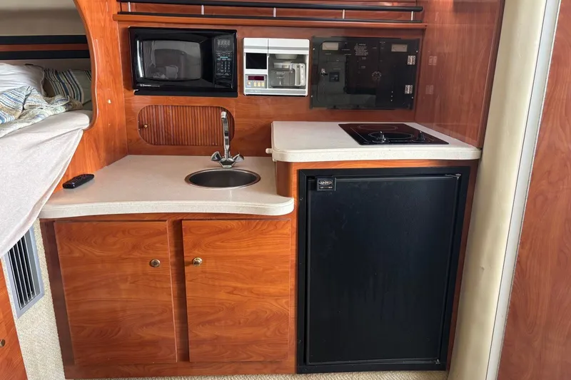 Slide: The Image of 2003 Rinker Fiesta Vee 312 boat kitchenette with sink, microwave, stove, and fridge. - 20