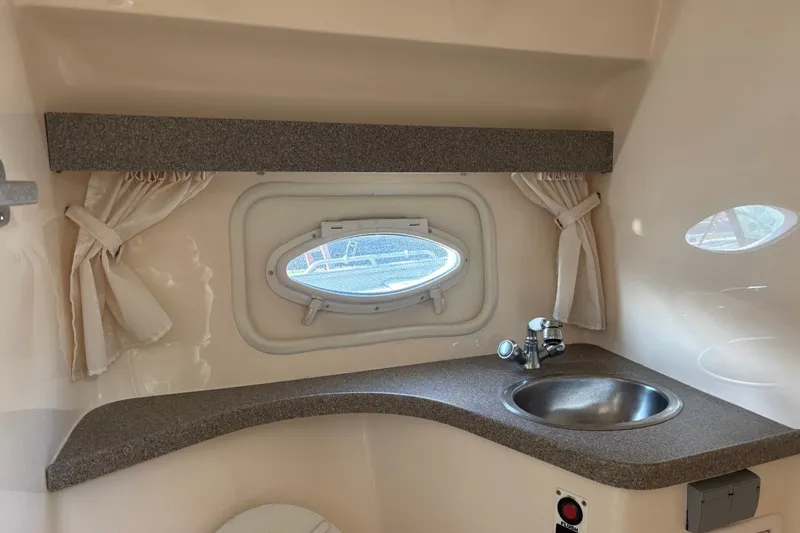 Slide: The Image of 2003 Rinker Fiesta Vee 312 boat interior with sink and porthole window. - 23