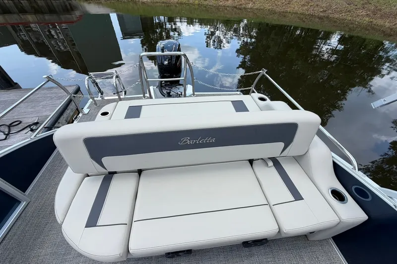 Slide: The Image of 2024 Barletta A22UC pontoon boat with plush seating, docked by a calm waterway. - 10