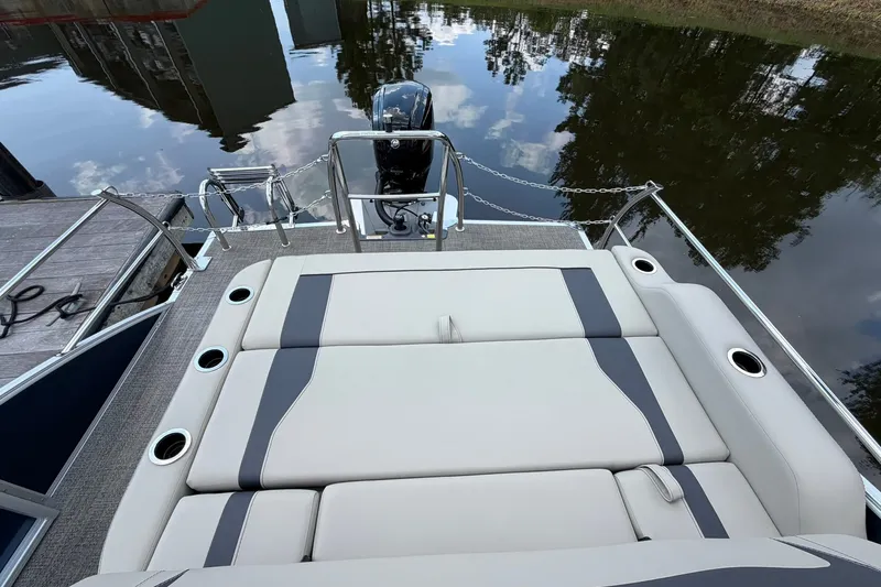 Slide: The Image of 2024 Barletta A22UC boat with cushioned seating and motor, docked by calm water. - 11