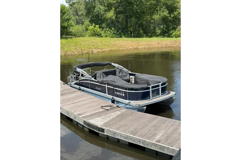 Slide: The Image of 2024 Barletta A22UC pontoon boat docked on a calm lake. - 2