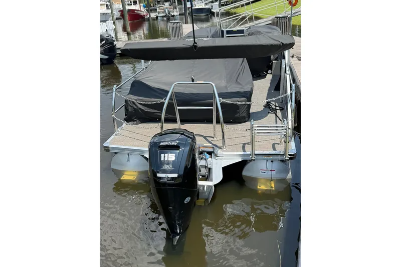 Slide: The Image of 2024 Barletta A22UC pontoon boat with Mercury 115 outboard engine, docked and covered. - 14