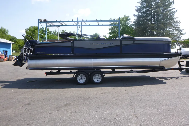 The Image of 2027 Premier 250 Sunsation RS - CL pontoon boat on trailer, parked outdoors. - 1