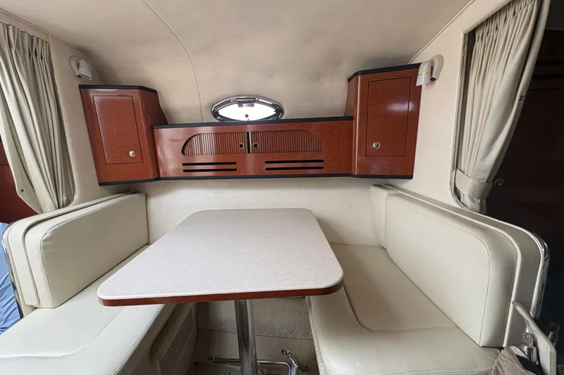 Slide: The Image of 2004 Sea Ray Sundancer 280 cabin interior with dining area and wooden cabinets. - 15