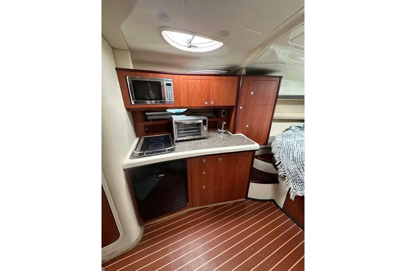 Slide: The Image of Interior of 2008 Monterey 330 Sport Yacht with kitchenette, featuring wood cabinetry and modern appliances. - 24