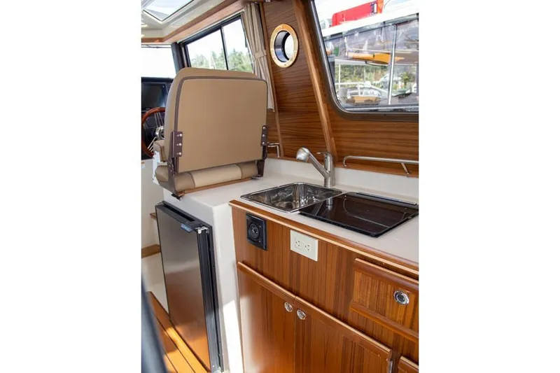 Slide: The Image of Manufacturer Provided Image: 2025 Ranger Tugs R-25 interior with kitchenette, sink, and wooden cabinetry. - 15