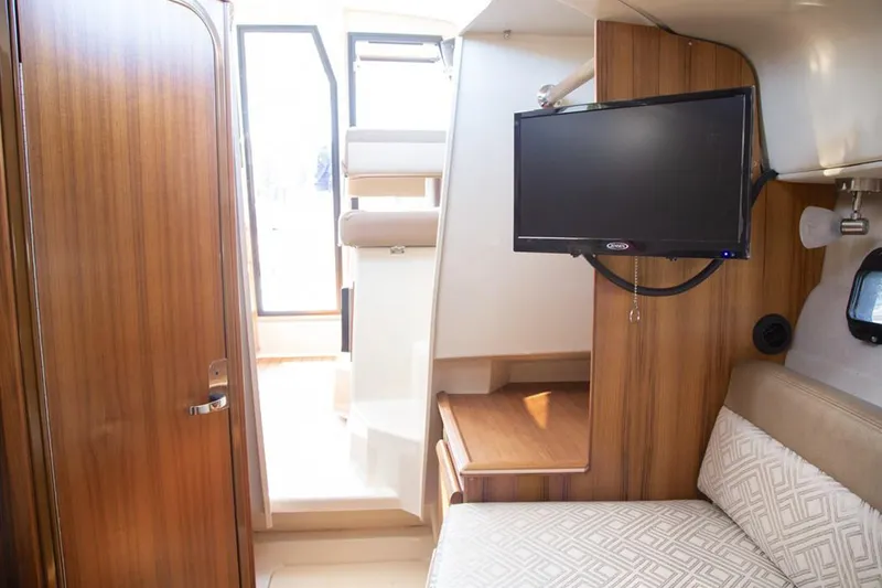 Slide: The Image of Manufacturer Provided Image: Interior of 2025 Ranger Tugs R-25 with TV, bed, and wooden finishes. - 16