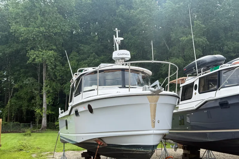 Slide: The Image of 2025 Ranger Tugs R-25 boat on land, surrounded by trees and other vessels. - 3
