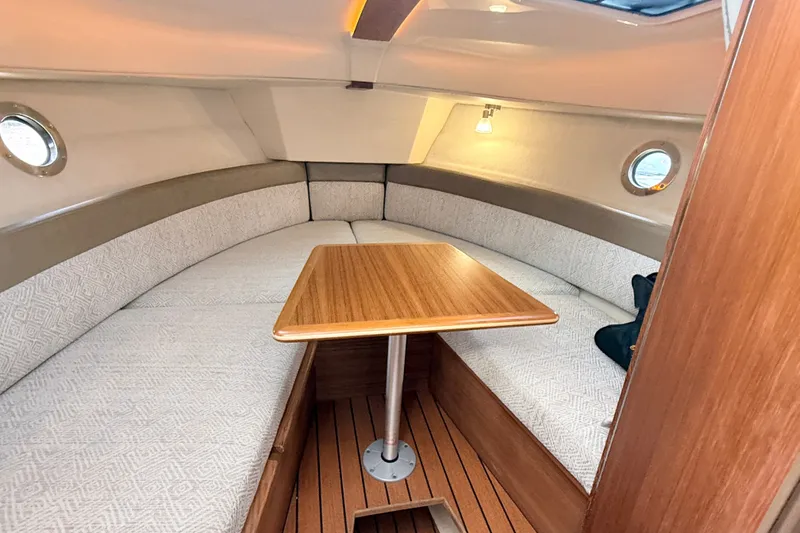 Slide: The Image of 2025 Ranger Tugs R-25 cabin interior with cozy seating and wooden table. - 17
