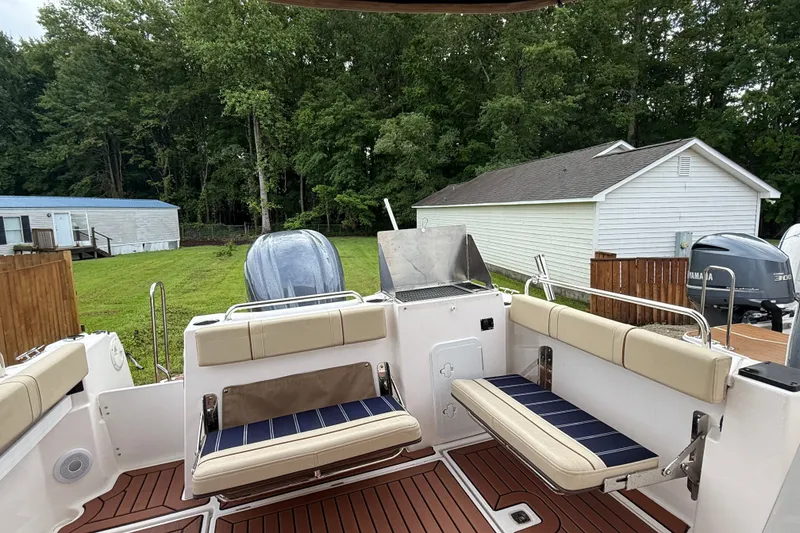 Slide: The Image of 2025 Ranger Tugs R-25 boat interior with seating and outdoor grill, surrounded by greenery. - 10