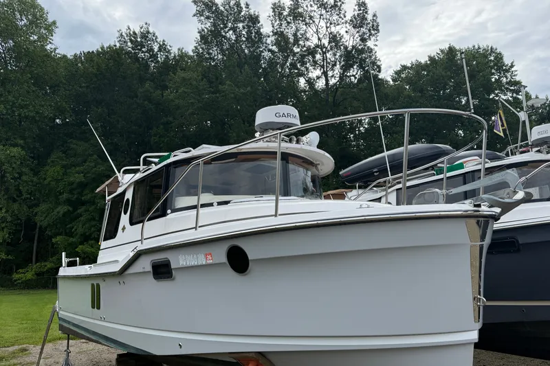 Slide: The Image of 2025 Ranger Tugs R-25 boat docked, surrounded by lush green trees. - 1